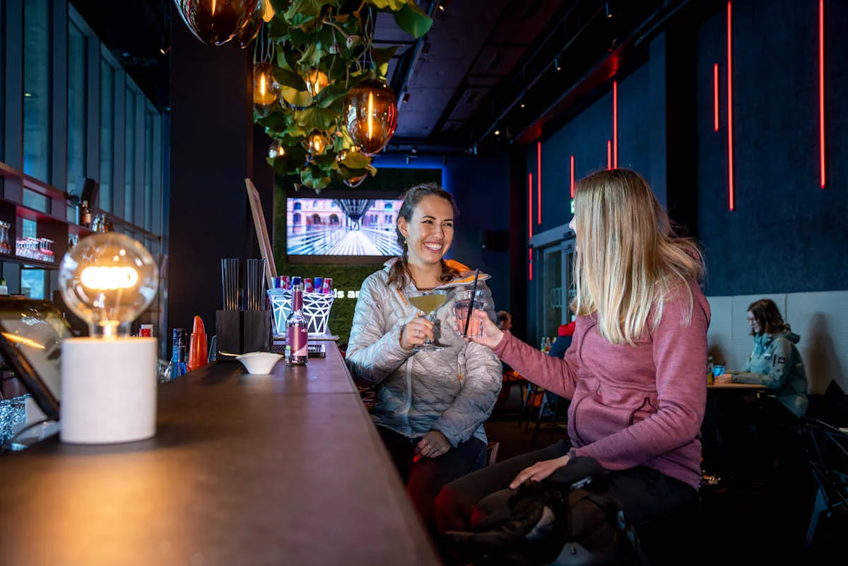 Two women raising their cocktails at the counter of the e-tron energy bar.
