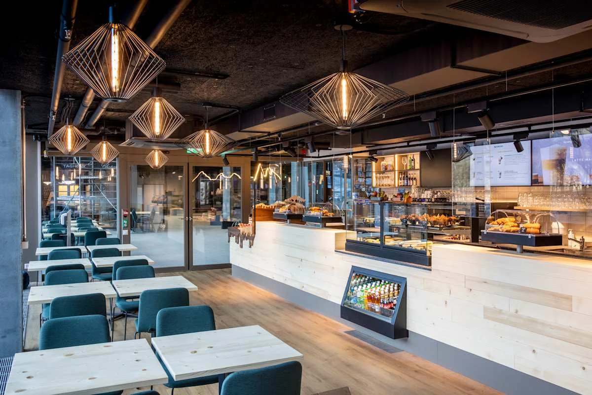 Modern bistro at Grindelwald Terminal with a seating area, counter and display cases featuring snacks and baked goods.